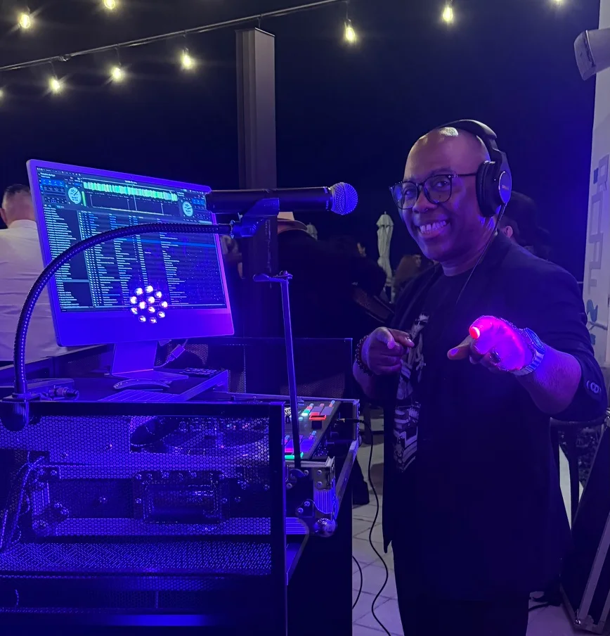 ShaCoda at his DJ booth under string lights, pointing to the dance floor